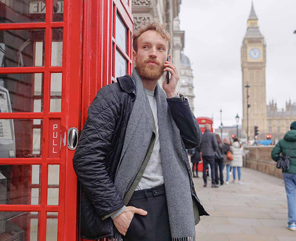 Vendere nel Regno Unito 1 Imprenditore al telefono a Londra, vicino a una cabina rossa, simbolo dell'espansione per vendere online nel Regno Unito