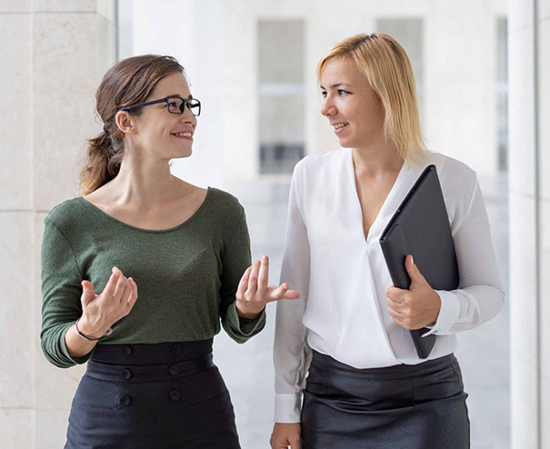 Solutions fiscales complémentaires 1 Due professioniste conversano sorridendo in un ambiente lavorativo, simbolo di collaborazione e consulenza aziendale